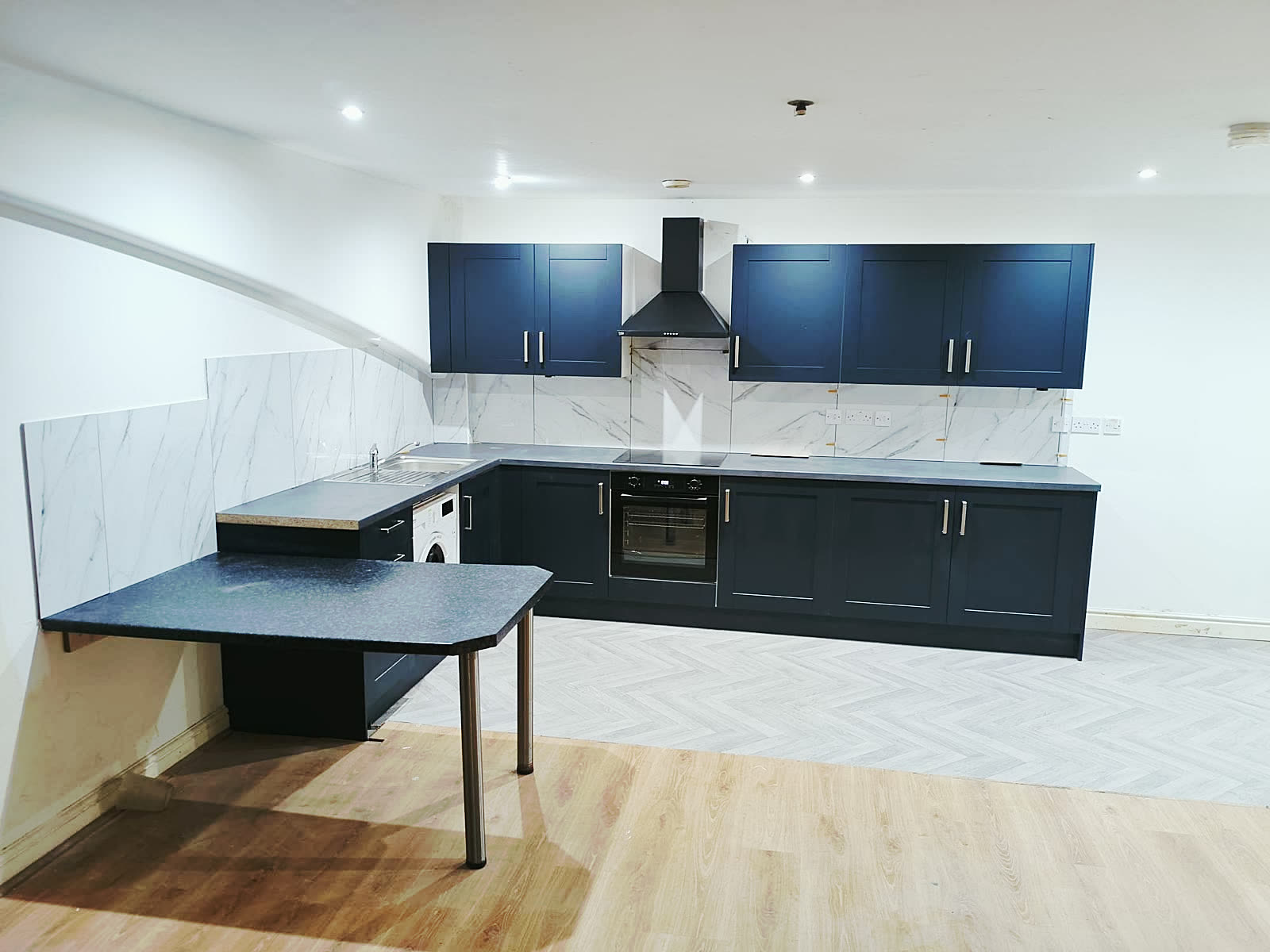 Finished navy shaker kitchen with marble-effect splashback fitted by Dunia Build