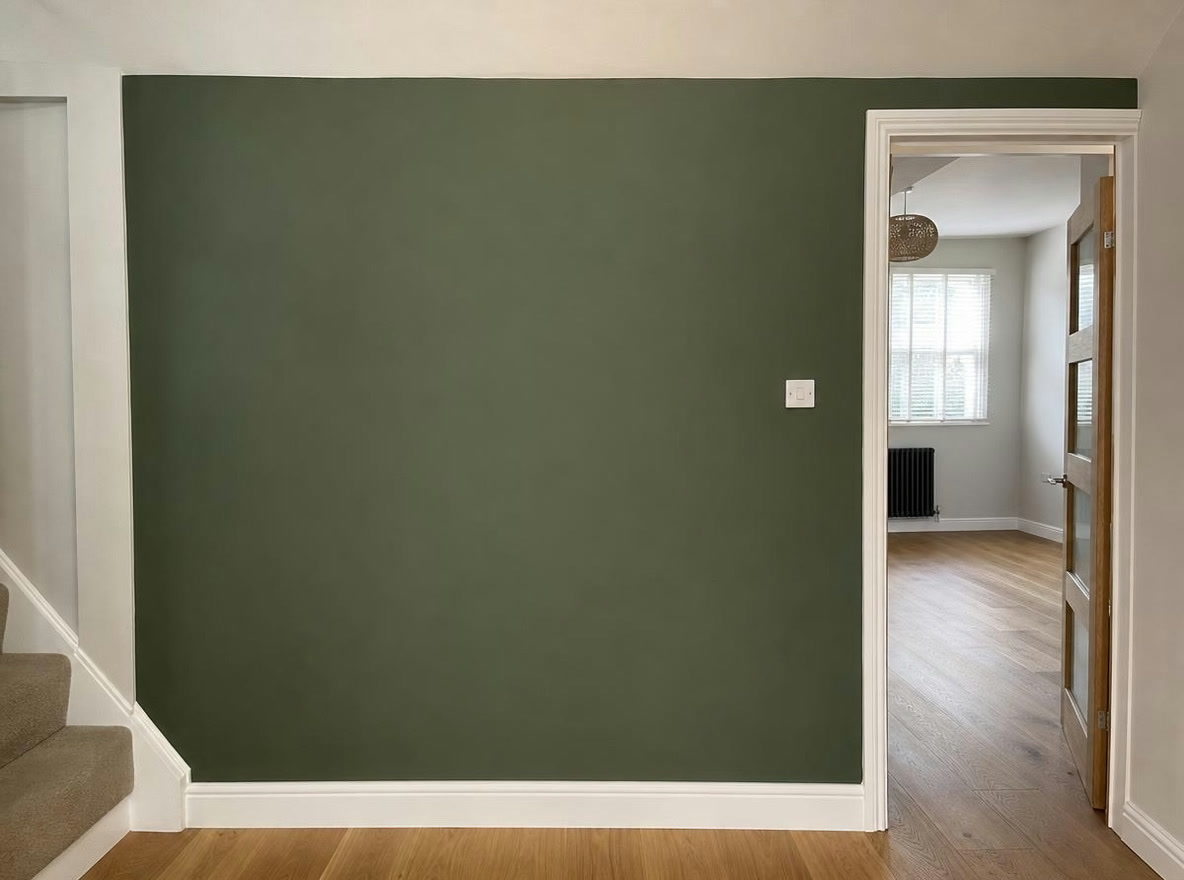 Hallway feature wall painted in deep green with crisp edges to white skirting and door frame